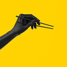 Black Hand Using Chopsticks Isolated On Yellow, Sushi Food At Japanese Restaurant Menu Concept 3d Illustration.
