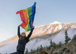 © Gabriel Trujillo/ADDICTIVE STOCK - Person on mountain peak waving LGBT flag