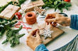 © PHILIPPE DEGROOTE/ADDICTIVE STOCK - Cropped anonymous person hands wrapping preparing christmas gifts with rope and christmas decorations