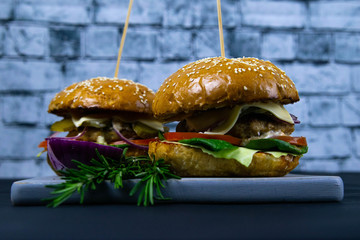 Two homemade beef burgers with mushrooms, micro greens, red onion on wooden cutting board