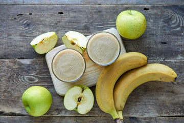 Wall Mural - Banana smoothie with green apples on a wooden table