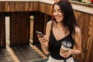 Wall Mural - Beautiful woman using phone and drink coffee on the streets.