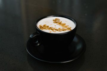 Wall Mural - black cup of cappuccino with a saucer on a table with a pattern of cinnamon