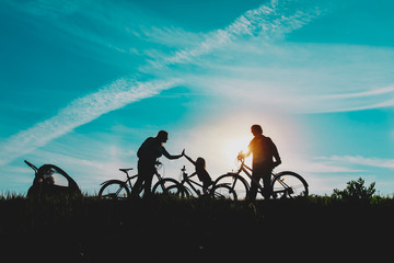 Wall Mural - Happy mom, dad with kids biking at sunset nature