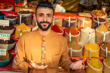 indian sallerman showing his small shop on arambol goa market