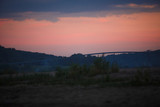 Fototapeta Na ścianę - Overpass across the river against a pink sky. Bridge at sunset