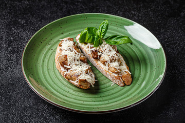 Italian Cuisine. Classic italian atipasta or tapas appetizer, baguette with mushrooms, parmesan and basil on a green plate. background image, copy space text