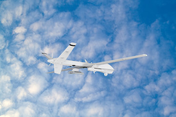 Wall Mural - RC military drone flies against the backdrop of blue peaceful sky with white clouds