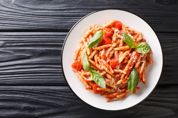 Pasta trofie recipe with tomato sauce, parmesan and basil close-up in a plate. Horizontal top view