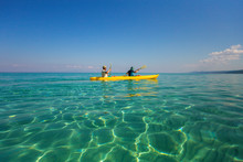 Father And Son Having Fun During Summer Beach Vacations. Happy Family Adventures Concept. Boy And Man Kayaking Together In Sunny Sea Amazing Clear Water Of Aegean Sea In Greece.