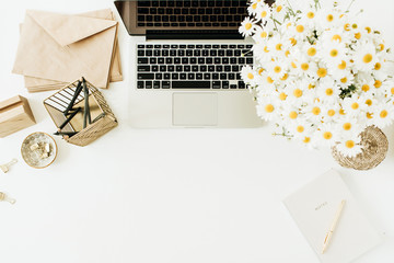 Wall Mural - Home office desk workspace with laptop, chamomile daisy flowers bouquet and notebook on white background. Flat lay, top view minimal hero header with copy space mockup.
