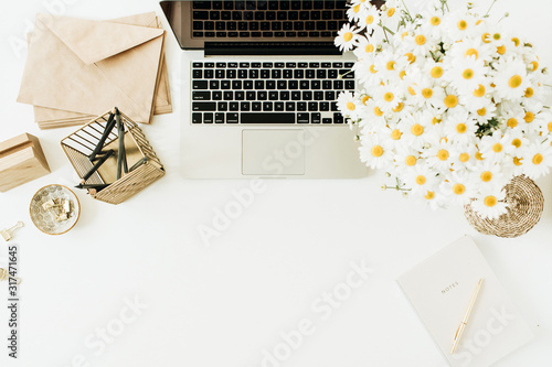 Cuadros en Lienzo Home office desk workspace with laptop, chamomile daisy flowers bouquet and notebook on white background