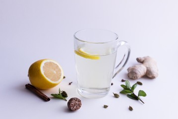 Wall Mural - Healthy drink in glass made of boiled mint ginger, lemon spices on white background