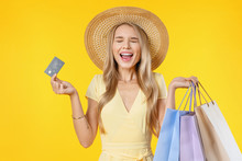 Excited Screaming Young Woman Holding Shopping Bags And Credit Card Standing Isolated Over Yellow Background