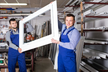 Wall Mural - Production workers in coverall with different   finished PVC profiles and windows at factory