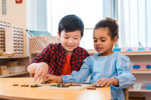 Children Playing With Wooden Board Game At Table In Montessori Class