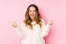 Young Curvy Woman Posing In A Pink Background Isolated Cheering Carefree And Excited. Victory Concept.