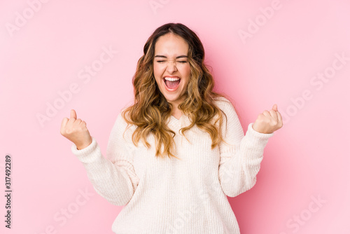 Cuadros en Lienzo Young curvy woman posing in a pink background isolated cheering carefree and excited