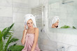 © deniskomarov - Young beautiful smiling woman talking mobile phone in bathroom after shower home portrait. Pretty girl wearing bath towel on head and body. Communication and nice conversation. Friend daily news