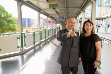 Poster - Mature Asian businessman and mature Asian woman exploring the city together