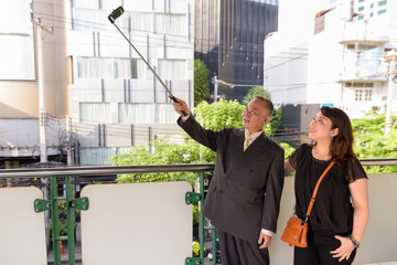 Wall Mural - Mature Asian businessman and mature Asian woman exploring the city together