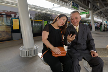 Poster - Mature Asian businessman and mature Asian woman exploring the city together