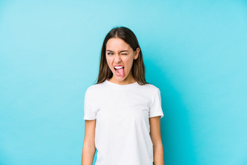 Wall Mural - Young caucasian woman  isolated funny and friendly sticking out tongue.