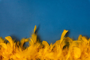 Yellow feather boa, carnival costume, on a blue background. Copy space.