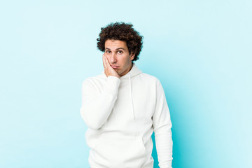 Young sporty man against a blue background who is bored, fatigued and need a relax day.