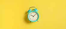 Turquoise Vintage Alarm Clock On Yellow Background. Top View. Flat Lay