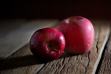 Fresh red apples fruit put on the old wooden floor in room which has dim light