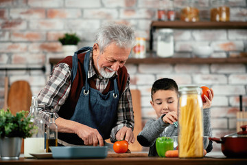 Wall Mural - Grandpa and grandson in kitchen. Grandfather and his grandchild having fun while cooking. 