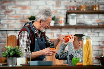 Wall Mural - Grandpa and grandson in kitchen. Grandfather and his grandchild having fun while cooking. 