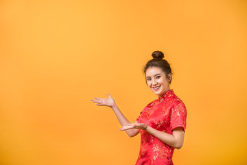 Asian woman smile in Chinese dress presenting free space yellow background. Chinese new year festival.