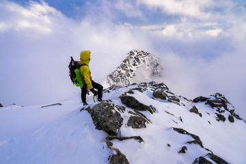 Wall Mural - Alpinist overlooking winter alpine like moutain landscape of High Tatras, Slovakia. Climber in winter mountains on snow and rocky peaks.