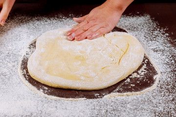 Woman smoothes dough with her hands.