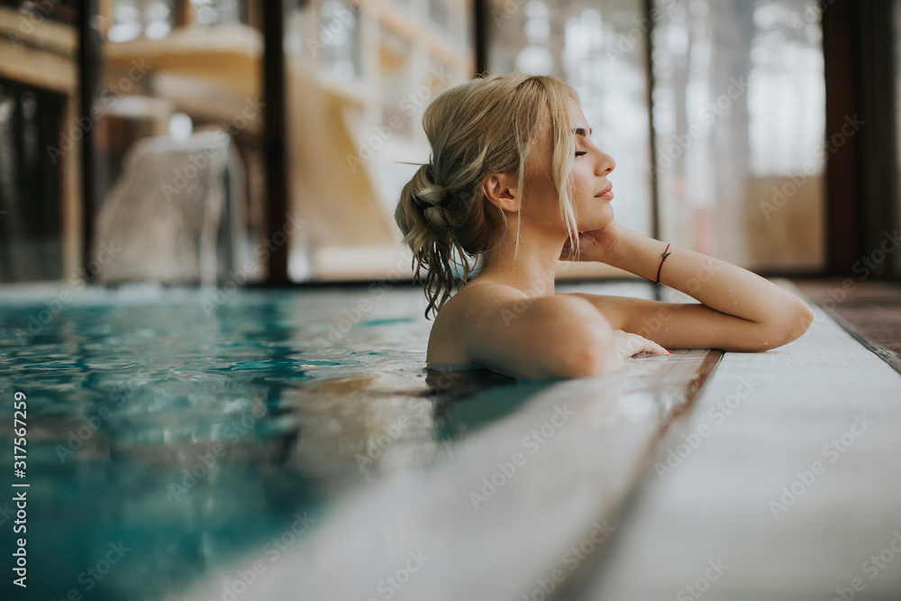 Young woman relaxing in spa swimming pool - obrazy, fototapety, plakaty 