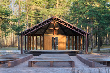 Wooden House Stage For Free Musicians Open Air Performances In Pine Forest In Sunlight, In Front Of Stage Many Benches Covered With Snow. Raising  Culture Of People, Music For All, Art Theater In Park