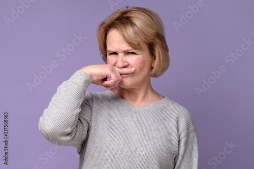 Fotografía Handsome expressive grandmother coering nose from hodor and bad smell from kitchen