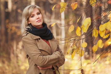 Wall Mural - Happy young fashion woman in beige coat walking in autumn park