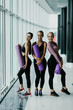 © F8  \ Suport Ukraine - Group of young sporty girls with yoga mats standing at gym. Female companions in gym resting after fitness, indoor full length, loft studio, copy space