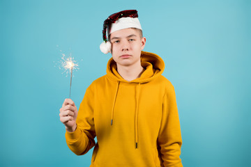 Wall Mural - sad teenager without mood holds a burning sparkler in his hand