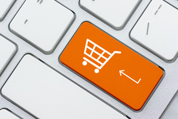 Online shopping / ecommerce and retail sale concept : White basket for checkout, shopping cart symbol on a laptop keyboard, depicts customers order / buy things from retailer sites using the internet