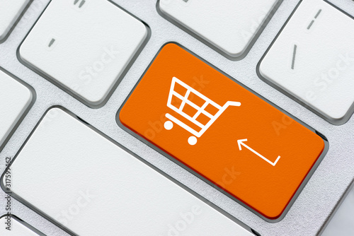 Online shopping / ecommerce and retail sale concept : White basket for checkout, shopping cart symbol on a laptop keyboard, depicts customers order / buy things from retailer sites using the internet