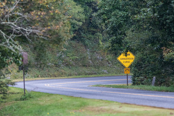 Yellow Dangerous Curve Sign Along a Mountain Roadway