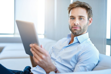 Wall Mural - Handsome young businessman looking at camera with digital tablet