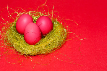 Bright colored eggs in a golden nest on a red background. happy easter concept. pattern, copy space