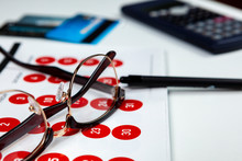 Pair Of Black Rimmed Spectacles Laying On A Calendar With Some Credit Cards
