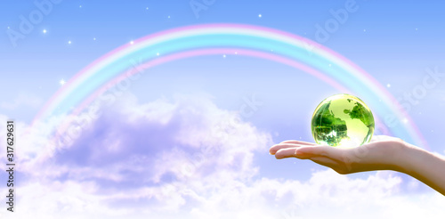 Card for World Earth Day. Clean air, Ozone Day concept. Saving environment, save and protect green planet and ecology. Earth crystal globe in human hand on stars, blue sky and rainbow background.
