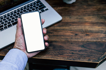 Mockup image blank white screen cell phone.man hand holding texting using mobile on desk at coffee shop.background empty space for advertise text.people contact marketing business,technology 